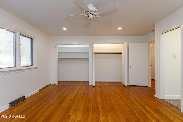 unfurnished bedroom with light wood-style flooring, visible vents, multiple closets, and recessed lighting