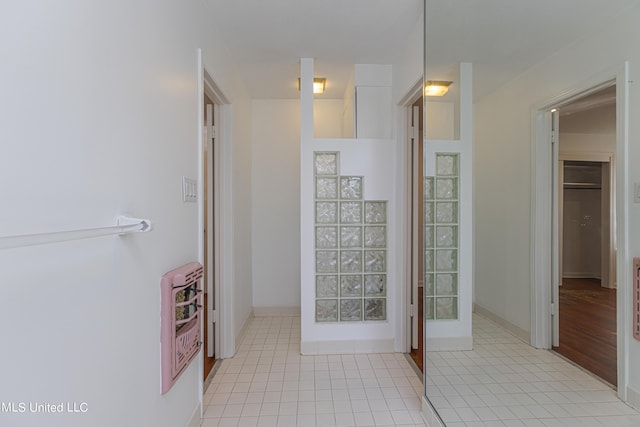 bathroom featuring baseboards, heating unit, and tile patterned floors