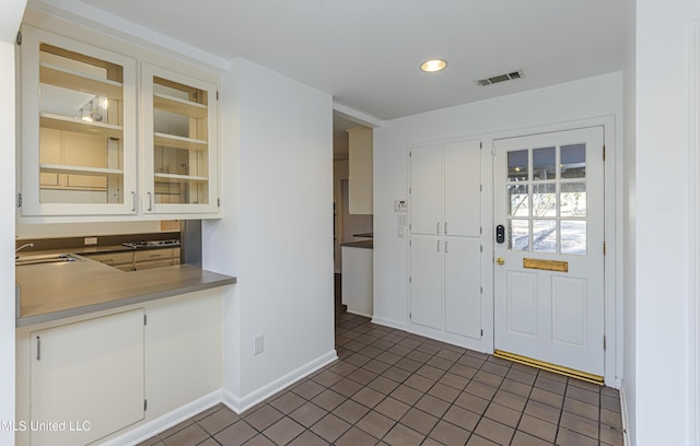 tiled foyer with baseboards, visible vents, and a sink