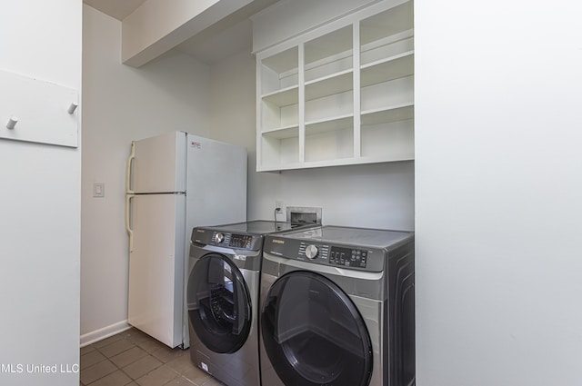 washroom featuring laundry area, dark tile patterned flooring, washing machine and dryer, and baseboards