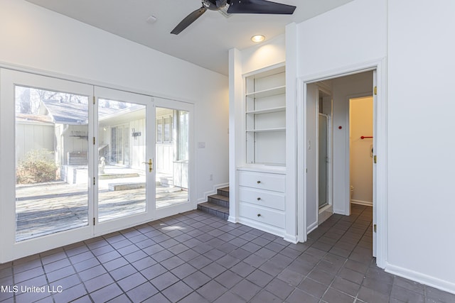 unfurnished room featuring built in shelves, dark tile patterned floors, baseboards, and a ceiling fan