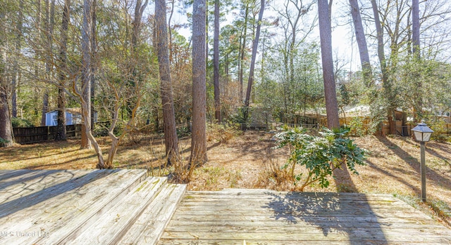 deck featuring a storage shed, fence, and an outbuilding