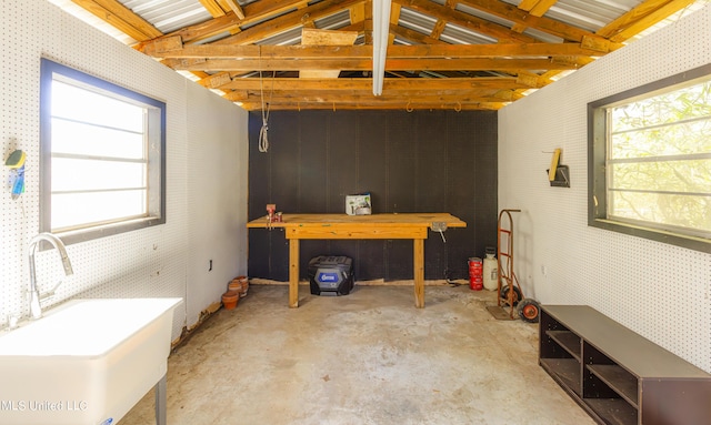 miscellaneous room with a sink, a healthy amount of sunlight, concrete flooring, and a workshop area