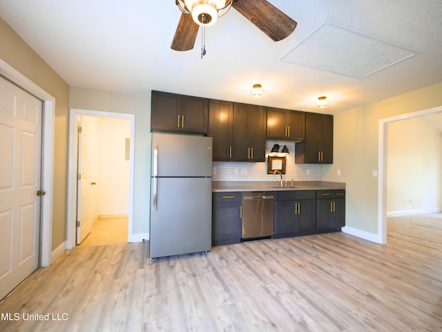 kitchen with light wood-style flooring, a sink, stainless steel appliances, decorative backsplash, and ceiling fan