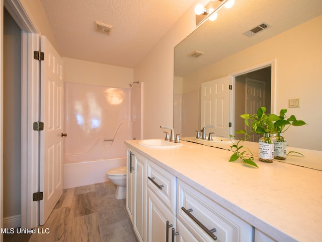 full bath with visible vents, toilet, vanity, and a textured ceiling