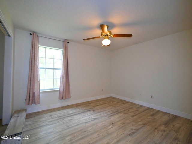 empty room featuring baseboards, wood finished floors, and a ceiling fan