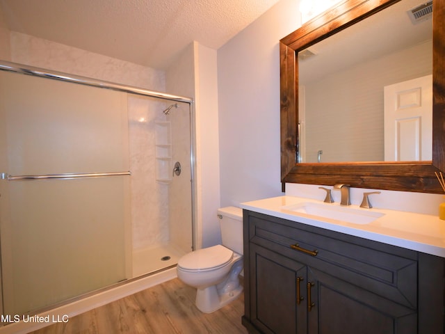 full bath with wood finished floors, visible vents, a stall shower, a textured ceiling, and toilet