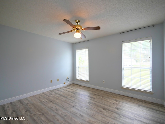 empty room featuring a ceiling fan, wood finished floors, baseboards, and a textured ceiling