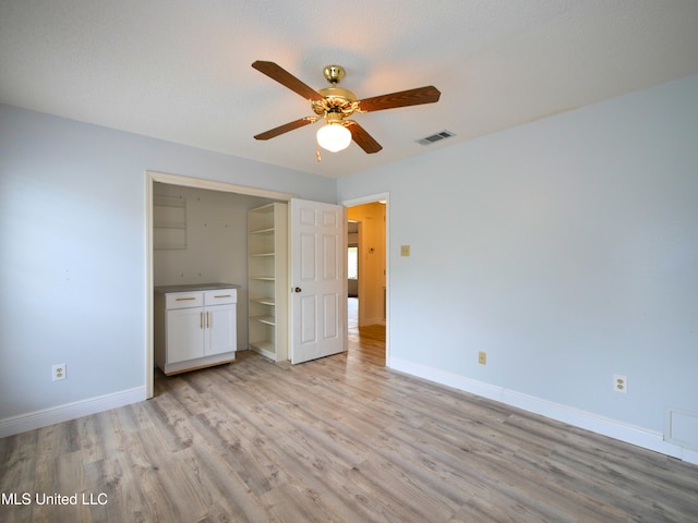 unfurnished bedroom featuring visible vents, baseboards, a ceiling fan, and light wood finished floors