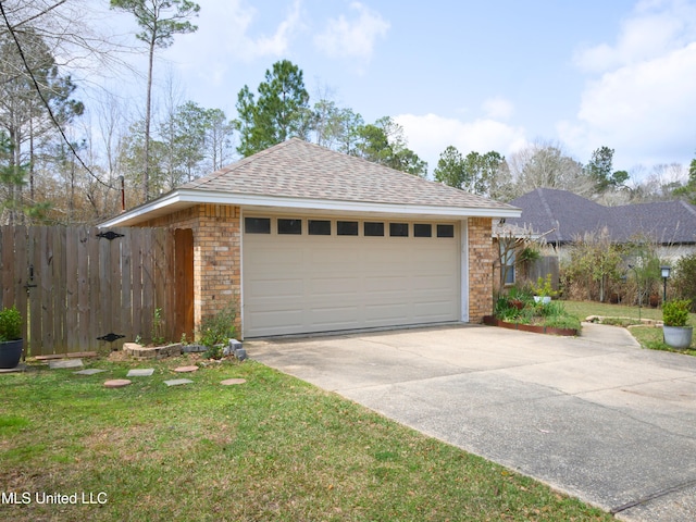 garage with concrete driveway and fence