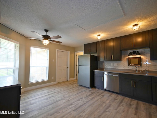 kitchen featuring ceiling fan, decorative backsplash, appliances with stainless steel finishes, light wood-style floors, and a sink