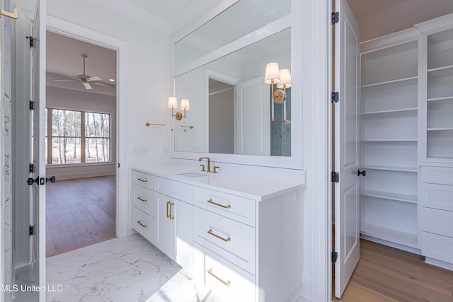 bathroom with vanity, wood-type flooring, ornamental molding, and ceiling fan