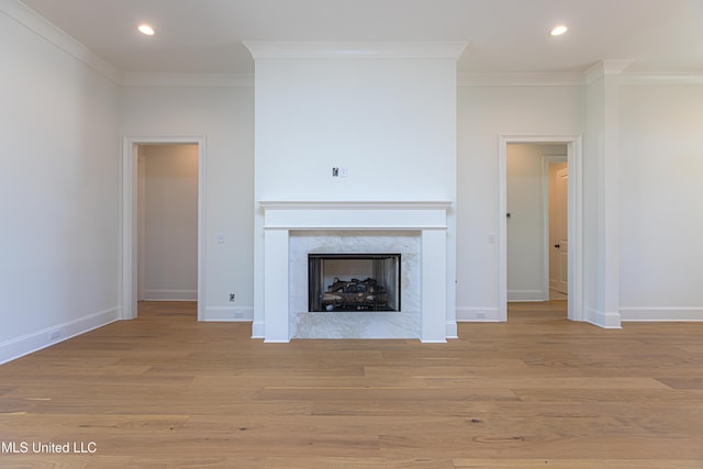 unfurnished living room featuring light hardwood / wood-style flooring, crown molding, and a high end fireplace