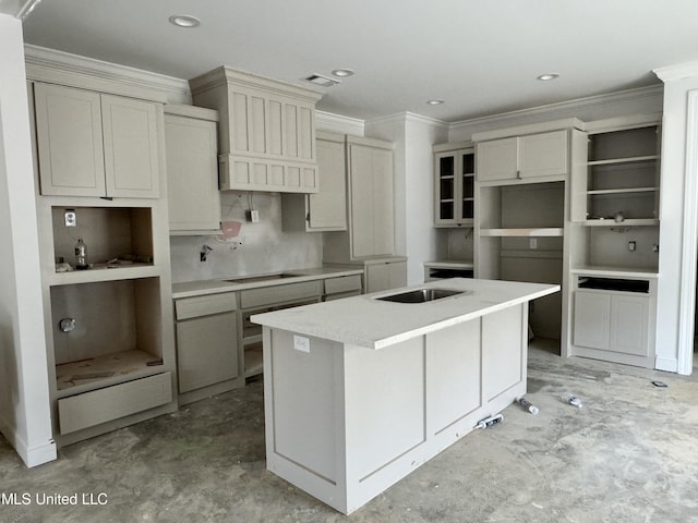 kitchen featuring cream cabinetry, cooktop, ornamental molding, and an island with sink