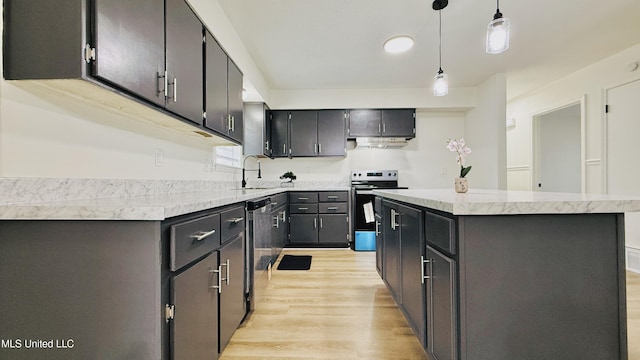 kitchen with stainless steel appliances, light wood-style flooring, light countertops, a sink, and a kitchen island