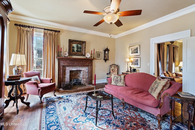 living area featuring a fireplace, wood-type flooring, ornamental molding, ceiling fan, and baseboards