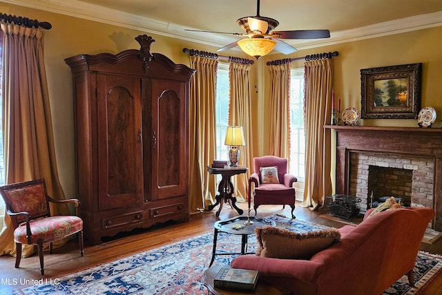 living area featuring ornamental molding, a ceiling fan, a fireplace, and wood finished floors