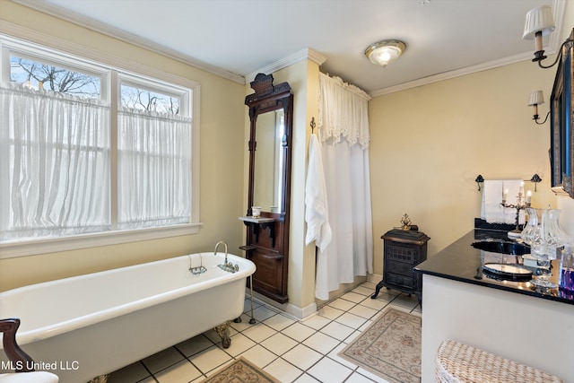 full bathroom featuring a freestanding tub, vanity, baseboards, tile patterned floors, and crown molding