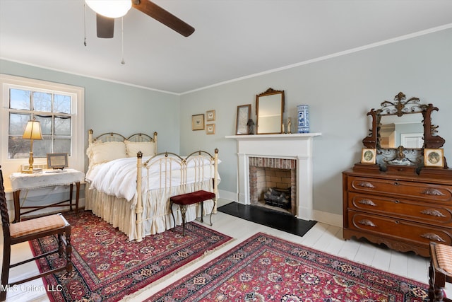 bedroom with a brick fireplace, ceiling fan, baseboards, and crown molding