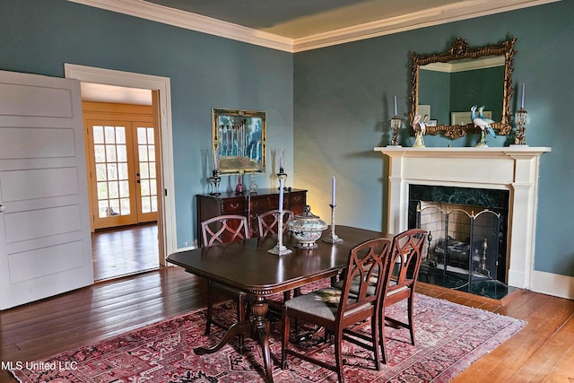 dining area featuring french doors, ornamental molding, a fireplace, and hardwood / wood-style floors