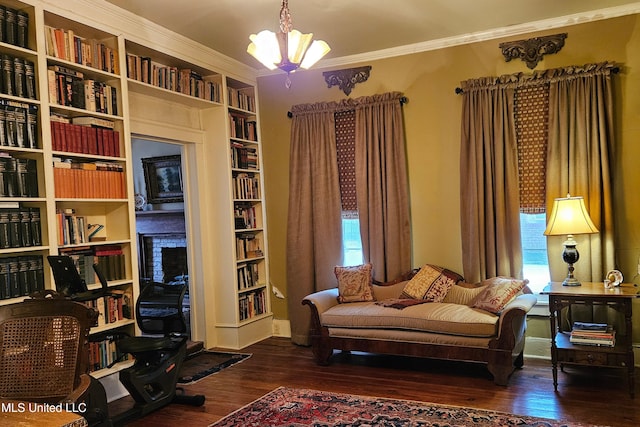 living area featuring a chandelier, ornamental molding, and wood finished floors