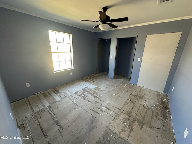 unfurnished bedroom featuring visible vents, multiple closets, a ceiling fan, and crown molding