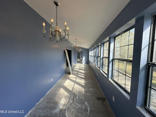 corridor featuring lofted ceiling and a chandelier