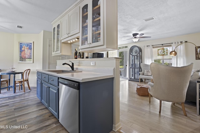 866 Washington St, Bay Saint Louis, MS 39520 - kitchen with stainless steel dishwasher, blue cabinets, wood finished floors, light countertops, and a textured ceiling