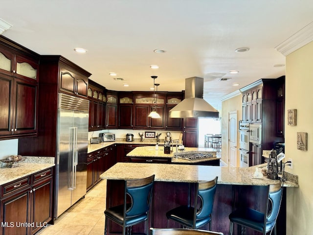 kitchen featuring appliances with stainless steel finishes, wall chimney exhaust hood, ornamental molding, and a kitchen breakfast bar