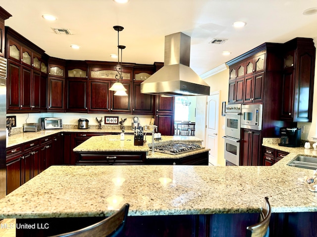 kitchen with island exhaust hood, a kitchen island with sink, ornamental molding, decorative light fixtures, and stainless steel appliances