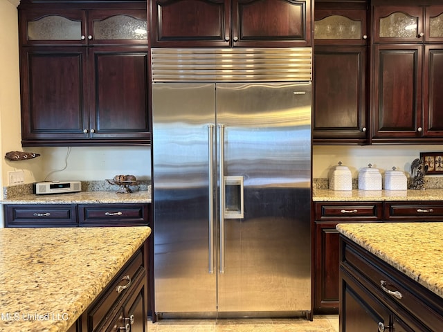 kitchen featuring stainless steel built in fridge, light stone countertops, and dark brown cabinetry