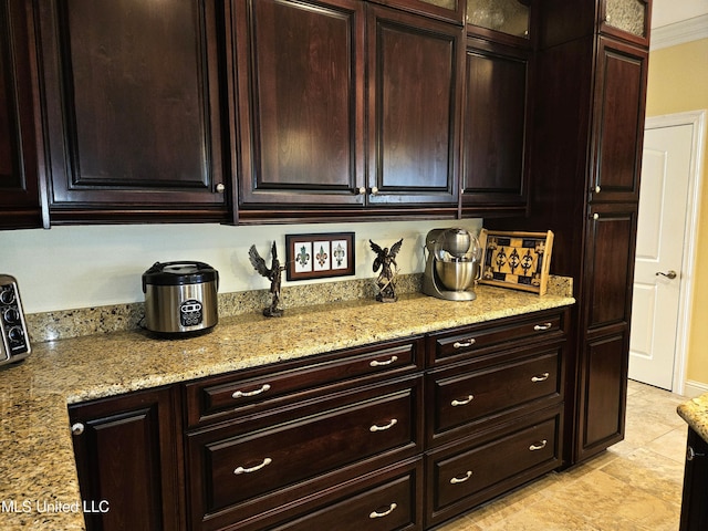 kitchen with dark brown cabinets, light stone countertops, and ornamental molding