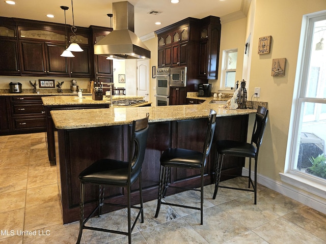 kitchen with kitchen peninsula, range hood, ornamental molding, dark brown cabinetry, and decorative light fixtures