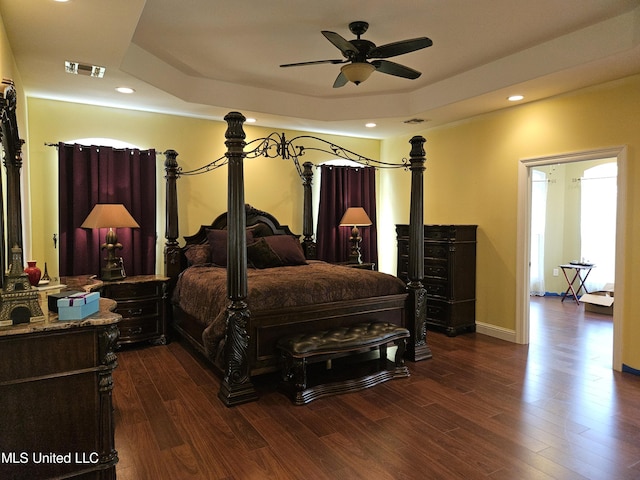 bedroom featuring ceiling fan, a raised ceiling, and dark hardwood / wood-style flooring