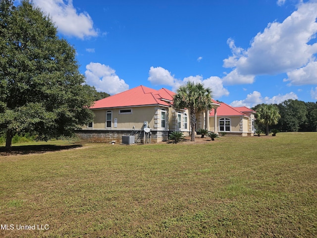 rear view of house featuring central AC and a yard