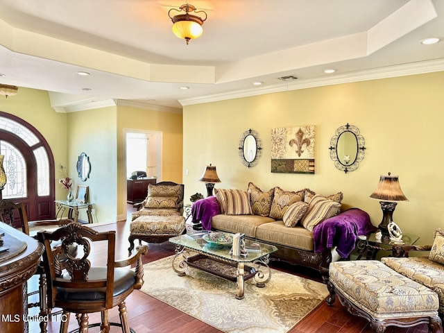 living room featuring hardwood / wood-style floors, crown molding, and a raised ceiling