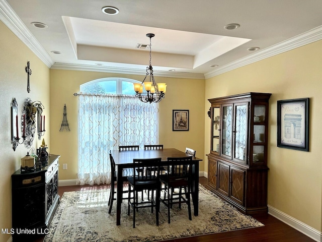 dining area featuring a tray ceiling, ornamental molding, dark hardwood / wood-style flooring, and a chandelier