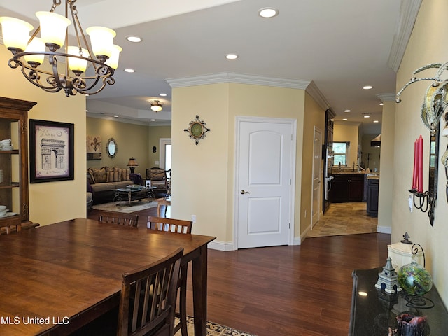 dining area featuring an inviting chandelier, crown molding, and dark hardwood / wood-style flooring