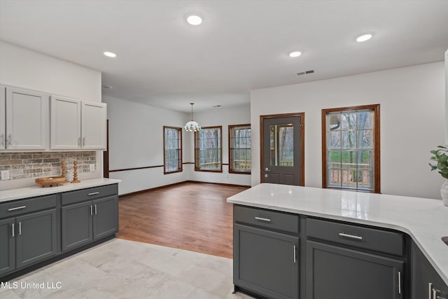 kitchen with light wood-type flooring, decorative light fixtures, tasteful backsplash, and gray cabinetry