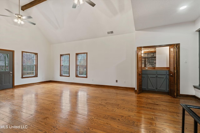 unfurnished living room with hardwood / wood-style floors, ceiling fan, beam ceiling, and high vaulted ceiling