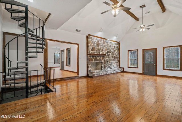 unfurnished living room with wood-type flooring, a wealth of natural light, ceiling fan, and beam ceiling