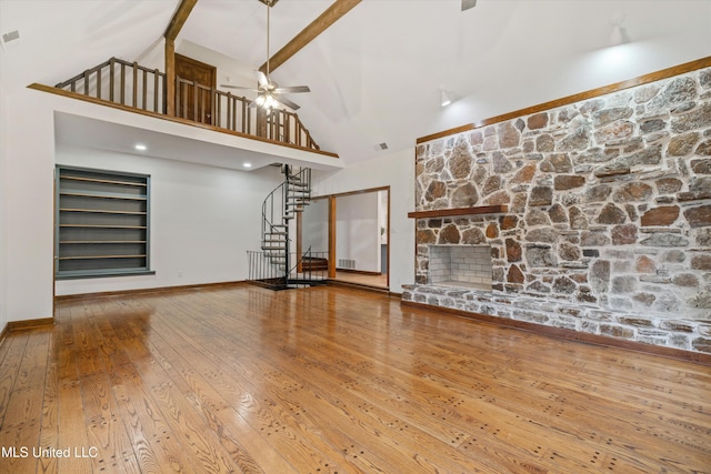 unfurnished living room with ceiling fan, high vaulted ceiling, beamed ceiling, hardwood / wood-style floors, and a fireplace