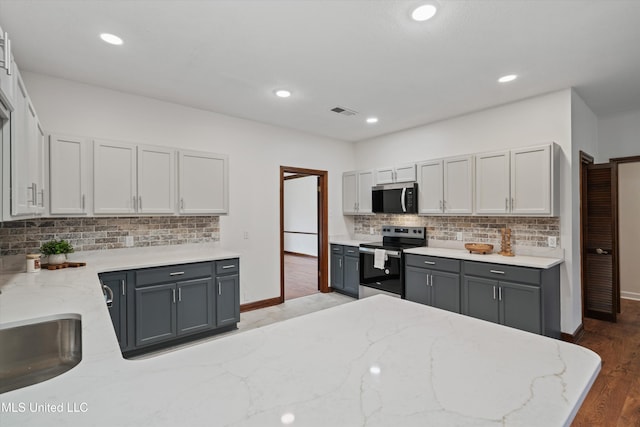 kitchen with light stone countertops, gray cabinets, stainless steel electric range oven, and hardwood / wood-style flooring