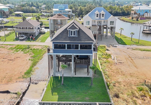 rear view of house with a residential view, a water view, dirt driveway, and roof with shingles