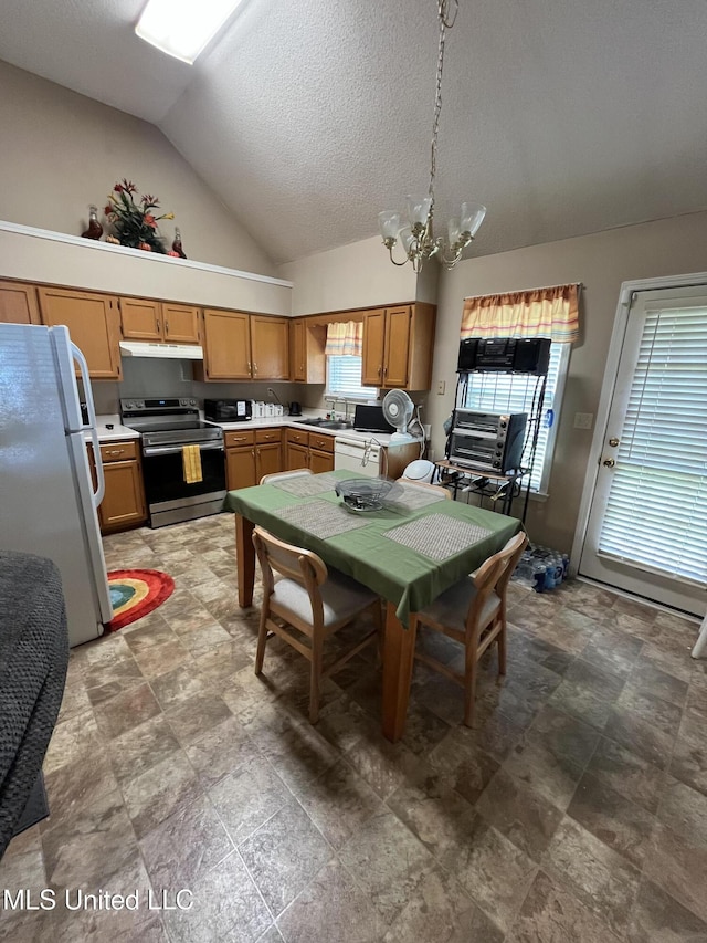 7605 Davis Pkwy, Southaven, MS 38671 - kitchen with electric range, freestanding refrigerator, vaulted ceiling, under cabinet range hood, and a chandelier