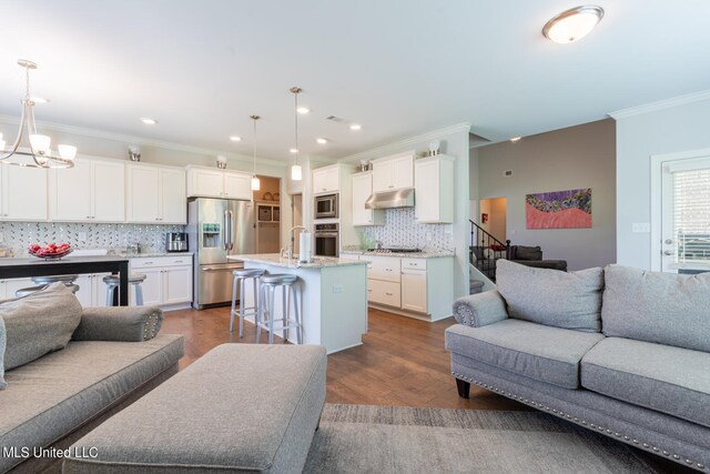 kitchen with appliances with stainless steel finishes, a breakfast bar, a center island with sink, and hanging light fixtures