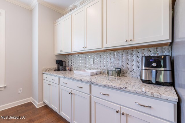 kitchen with decorative backsplash, ornamental molding, white cabinets, light stone counters, and dark hardwood / wood-style flooring