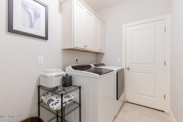 washroom featuring light tile patterned floors, washing machine and dryer, and cabinets