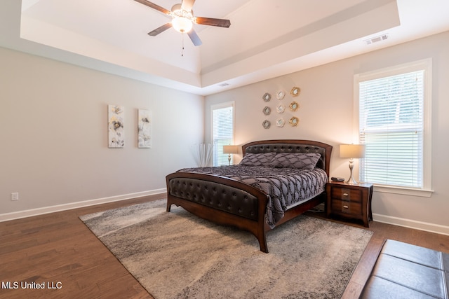 bedroom featuring ceiling fan, a tray ceiling, and dark hardwood / wood-style flooring