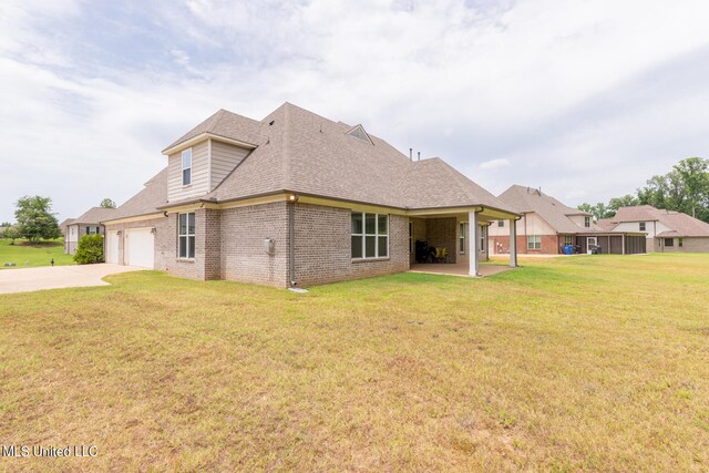 back of property with a patio area, a yard, and a garage